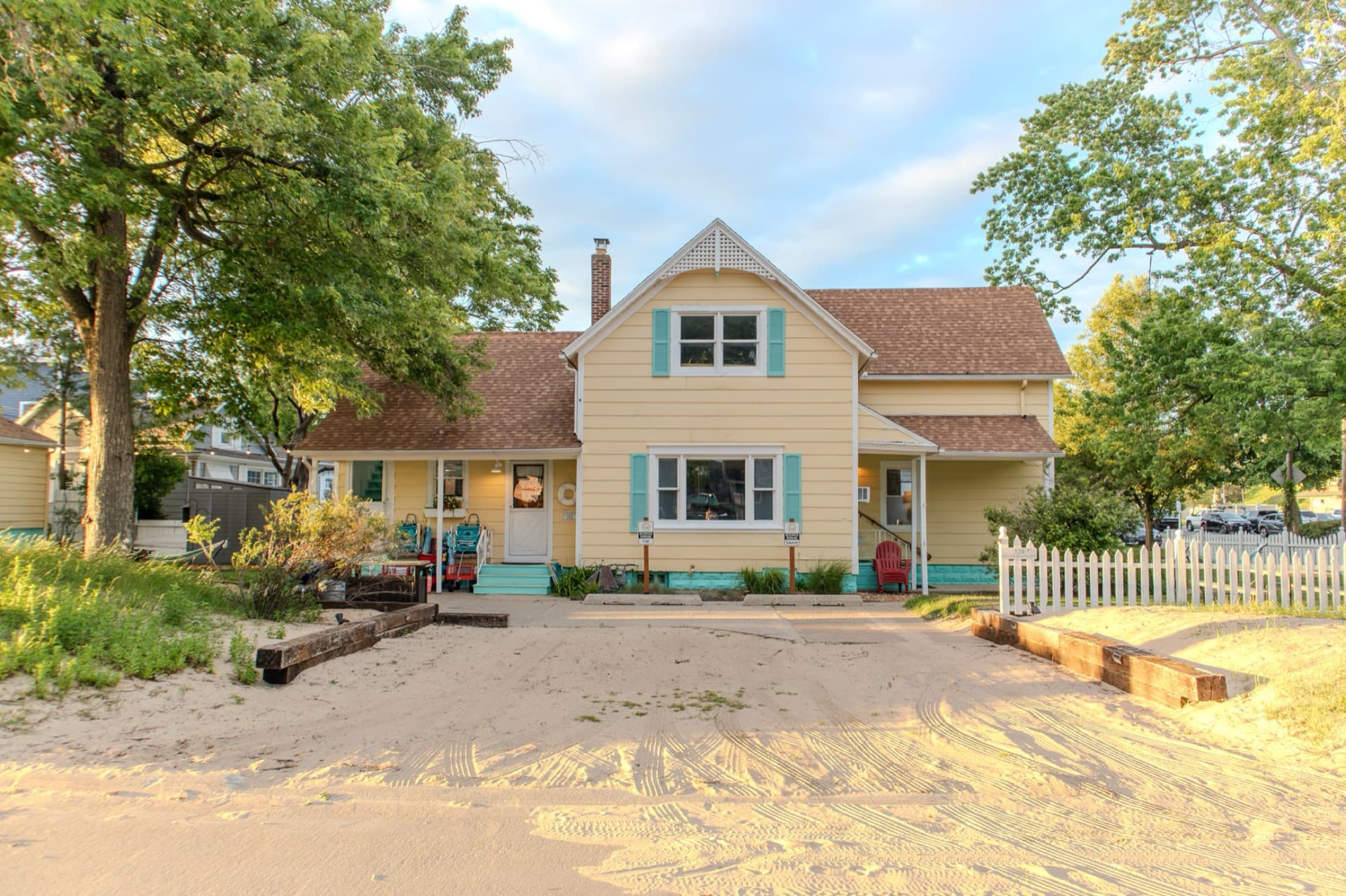 The yellow Silver Beach Inn cottage with turquoise trim and a sandy front approach